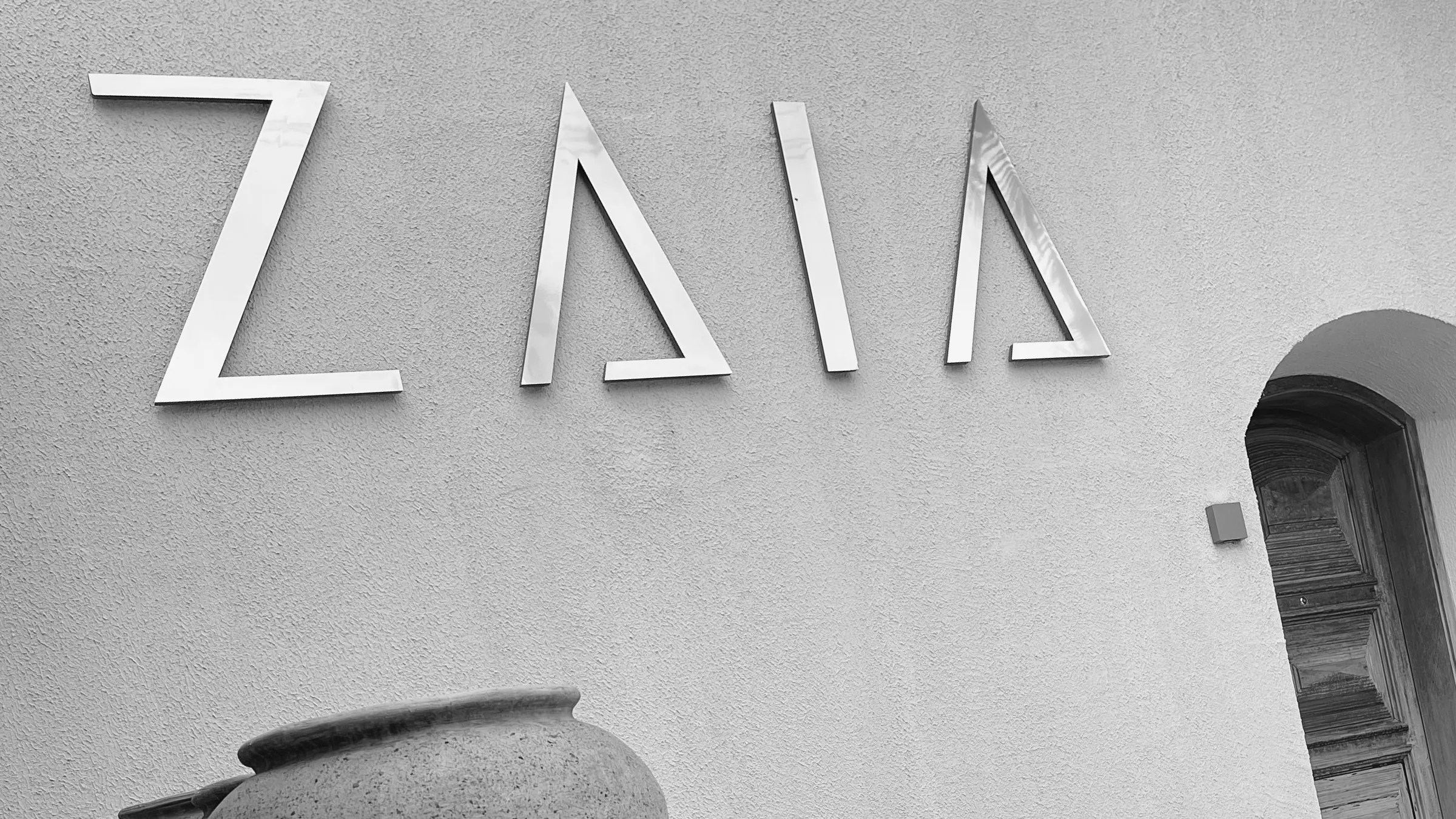 Fachada do consultório ZAIA com o letreiro tipográfico aplicado em metal, em preto e branco.